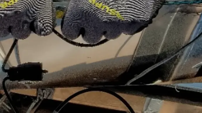 Installer in work gloves routing cables beneath a solar panel