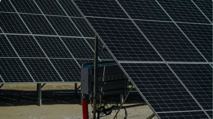 Inverter mounted on a post between two rows of solar panels