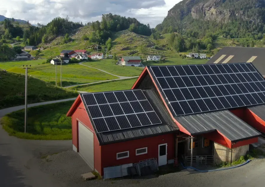 Låve med solcellepaneler på taket i et jordbrukslandskap